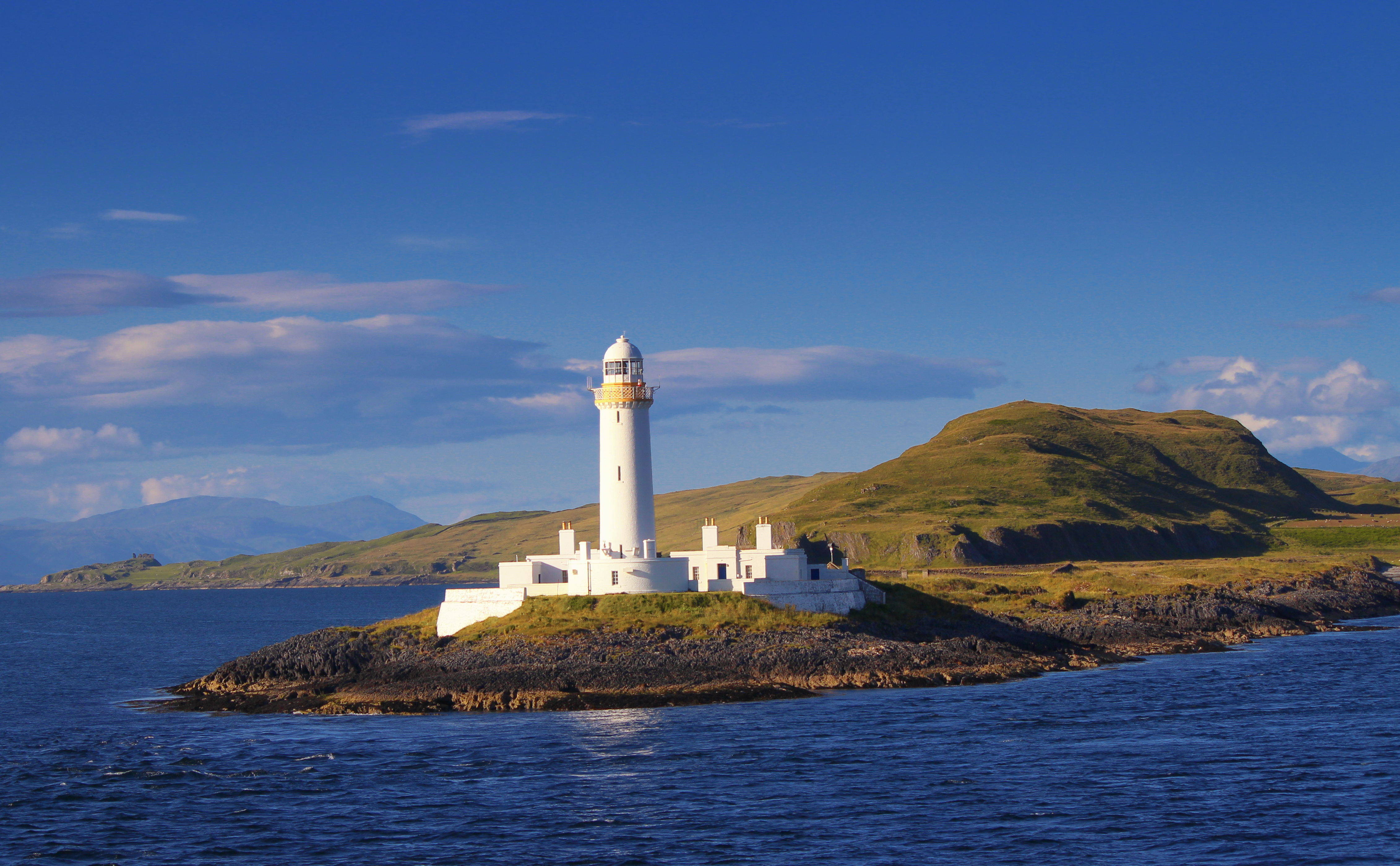 Lismore Lighthouse and its keeper houses on the low island of Eilean Musdile, seen from the water.