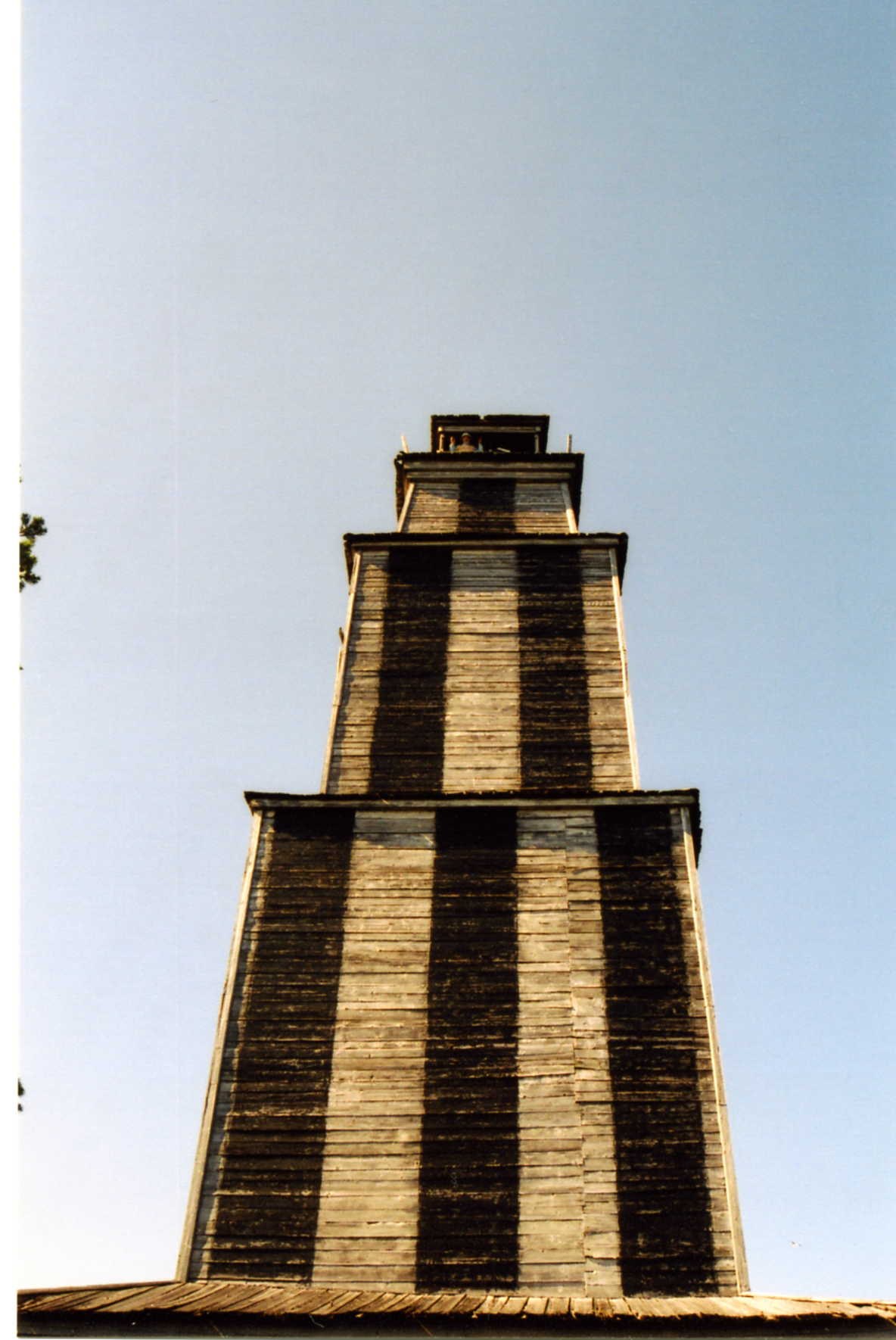 Low-angle view of the Vasilisin striped tower showing the lantern room and gallery at the top.